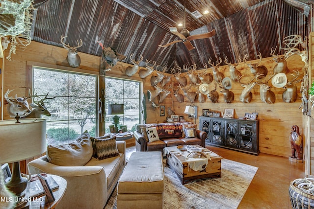 living room with wood walls, a healthy amount of sunlight, and high vaulted ceiling