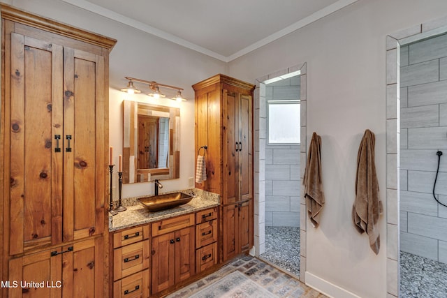 bathroom featuring a tile shower, crown molding, tile patterned flooring, and vanity