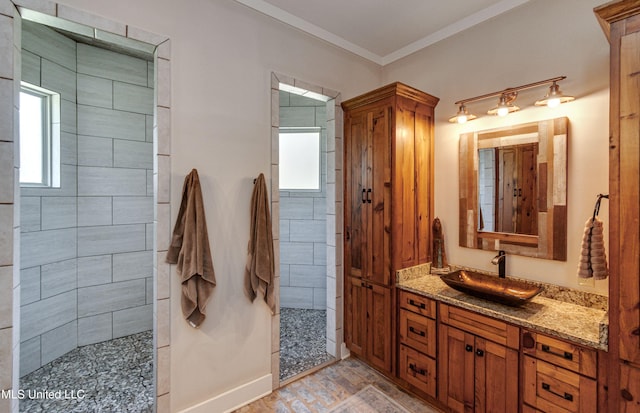 bathroom featuring vanity, a tile shower, and ornamental molding