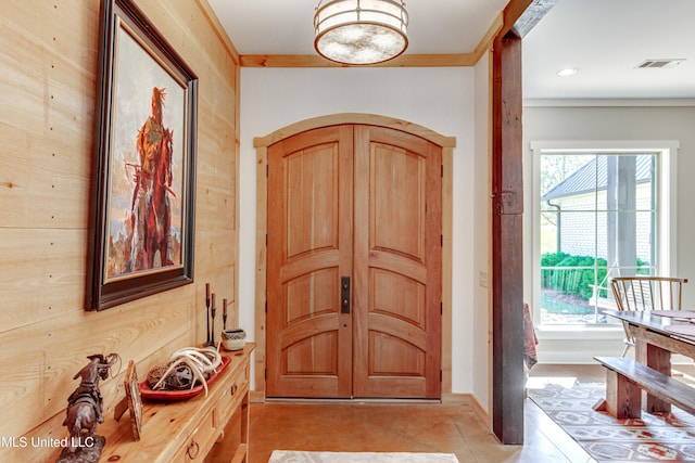 tiled foyer with wood walls and crown molding