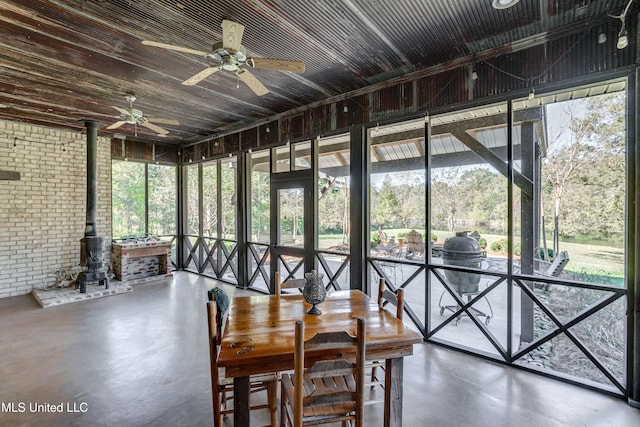 sunroom / solarium with ceiling fan and a wood stove