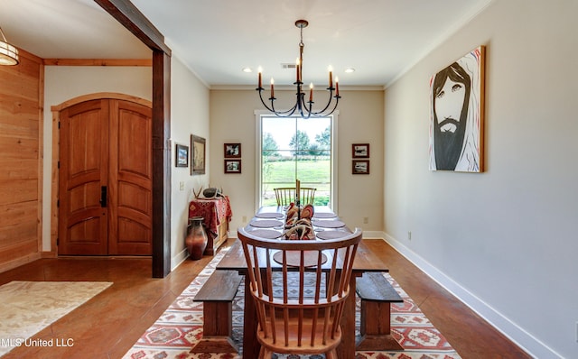 dining room featuring a chandelier, wooden walls, and ornamental molding