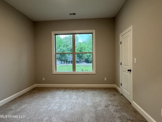 carpeted spare room featuring baseboards and visible vents