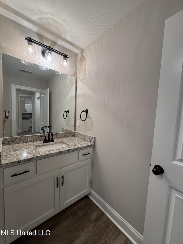 bathroom with vanity, baseboards, wood finished floors, and visible vents