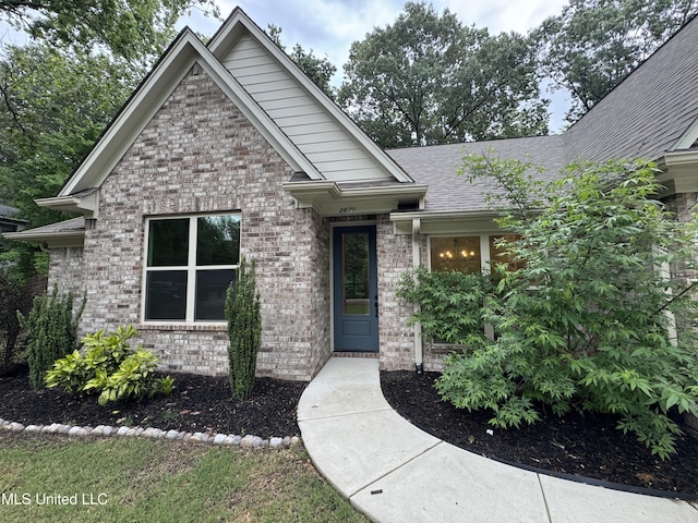 craftsman-style home featuring brick siding and roof with shingles