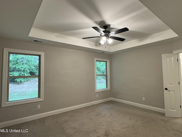 spare room featuring baseboards, a raised ceiling, ceiling fan, and light carpet