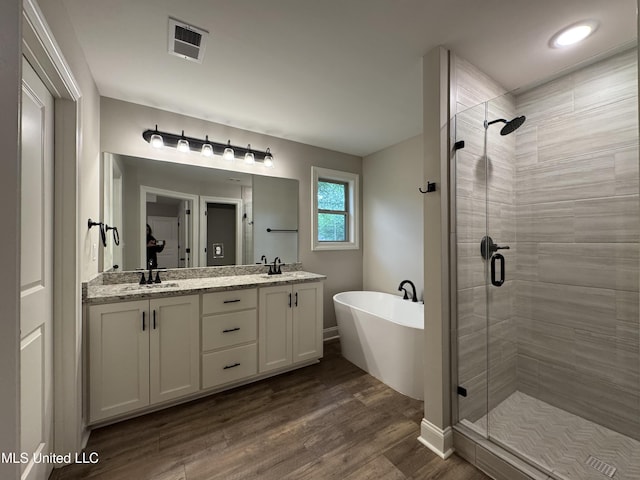 bathroom featuring visible vents, a sink, a freestanding bath, and a stall shower