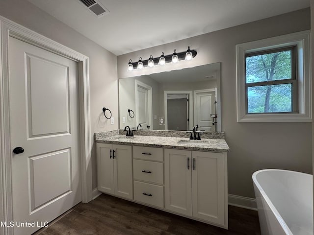 bathroom featuring double vanity, a sink, wood finished floors, and visible vents