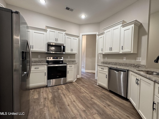 kitchen featuring visible vents, a sink, white cabinets, dark wood-style floors, and stainless steel appliances