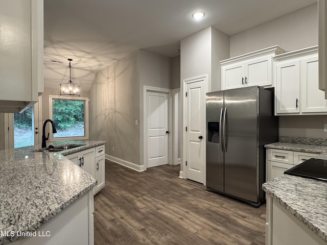 kitchen featuring light stone countertops, dark wood-style floors, stainless steel fridge, white cabinetry, and a sink
