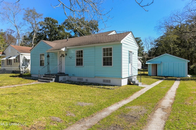 view of front of home with a storage shed, roof with shingles, crawl space, an outdoor structure, and a front yard