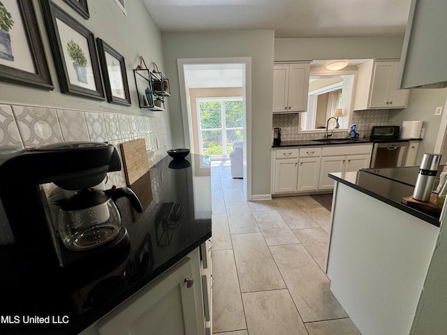 2293 Elm St, Hernando, MS 38632 - kitchen with a sink, dark countertops, decorative backsplash, white cabinets, and light tile patterned floors