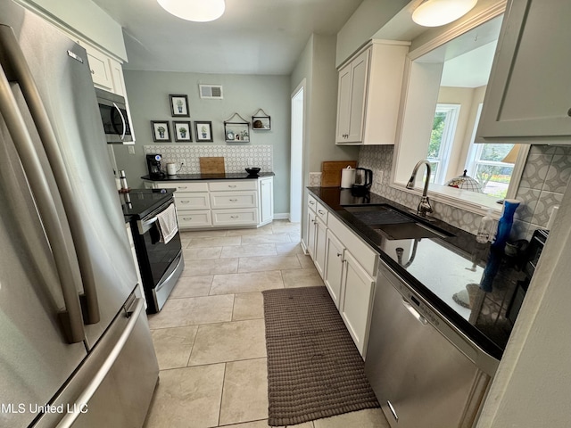 2293 Elm St, Hernando, MS 38632 - kitchen with stainless steel appliances, a sink, backsplash, dark countertops, and white cabinetry
