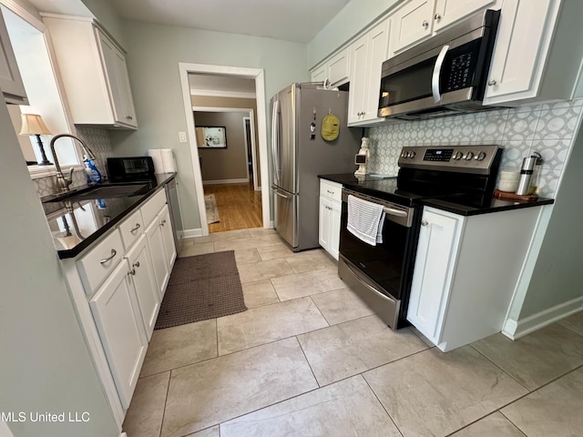 2293 Elm St, Hernando, MS 38632 - kitchen with appliances with stainless steel finishes, a sink, decorative backsplash, dark countertops, and baseboards