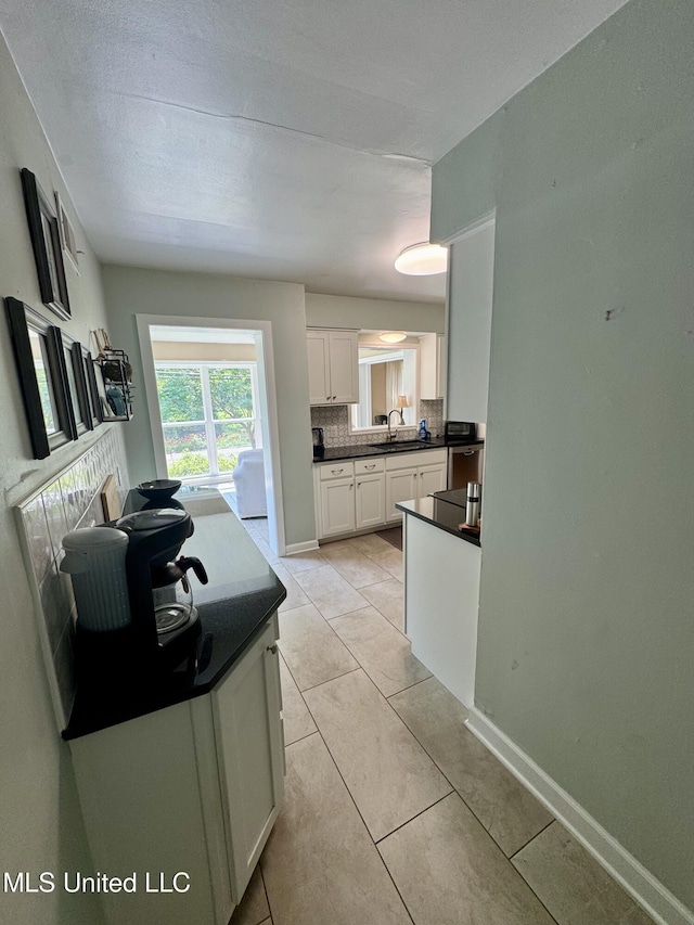 2293 Elm St, Hernando, MS 38632 - kitchen featuring dark countertops, a sink, white cabinetry, backsplash, and light tile patterned flooring