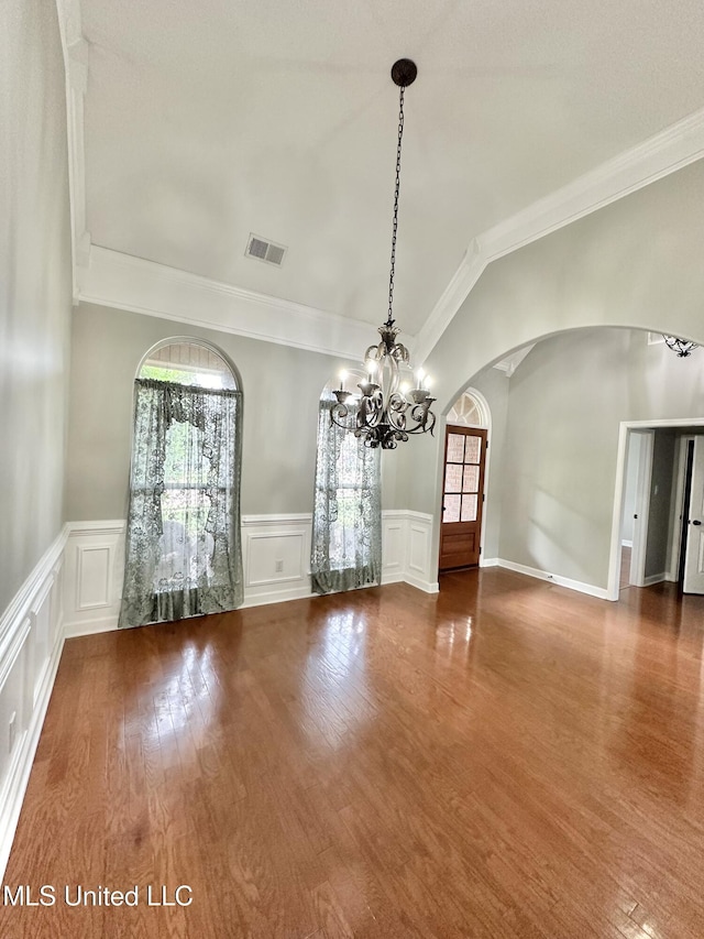 unfurnished room featuring visible vents, arched walkways, a healthy amount of sunlight, and wood finished floors