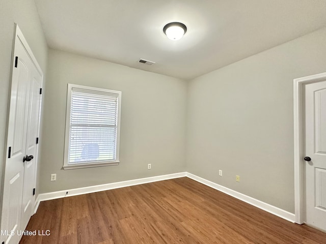 empty room featuring dark wood finished floors, baseboards, and visible vents