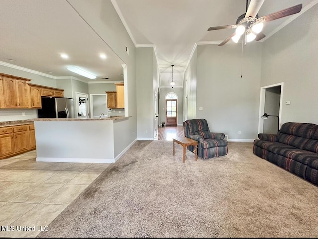 living room featuring light tile patterned floors, a ceiling fan, baseboards, ornamental molding, and light carpet