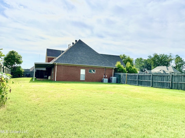 exterior space with brick siding, a lawn, roof with shingles, and fence