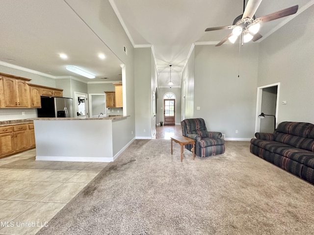 living room featuring ceiling fan, baseboards, ornamental molding, light carpet, and light tile patterned floors