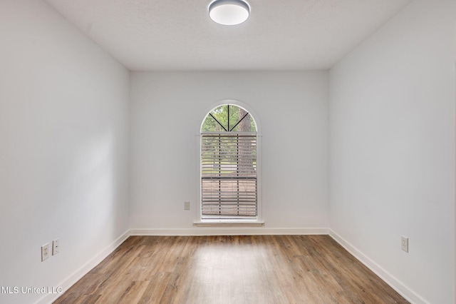 spare room featuring wood finished floors and baseboards