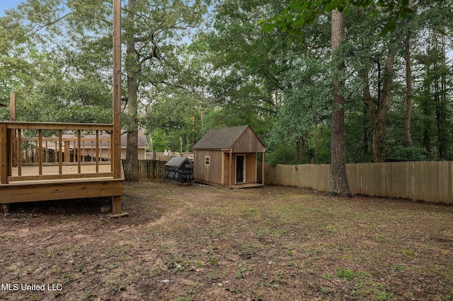 fenced backyard featuring a deck, a storage shed, and an outdoor structure
