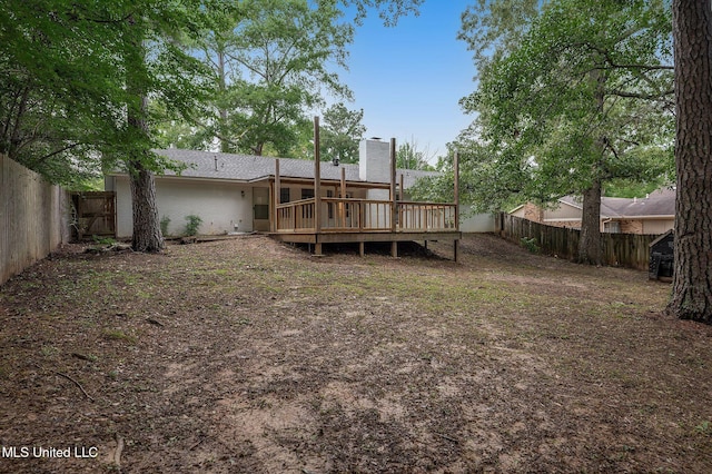 rear view of house with a fenced backyard, a wooden deck, and a chimney