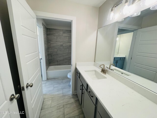 full bathroom featuring tiled shower / bath combo, vanity, and toilet