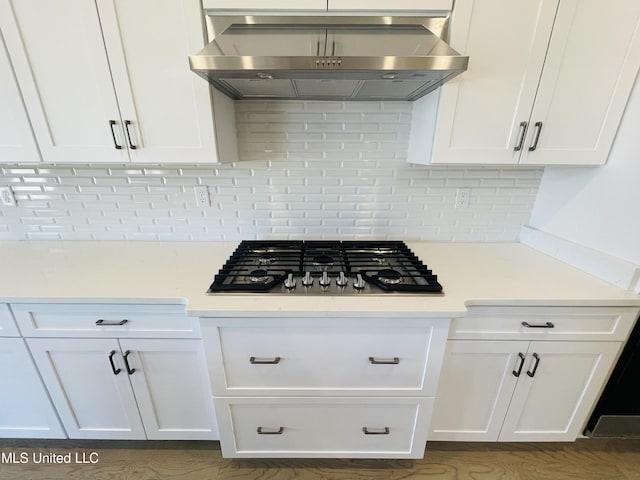 kitchen featuring extractor fan, white cabinets, stainless steel gas cooktop, and tasteful backsplash