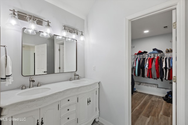 full bath with double vanity, baseboards, a sink, and wood finished floors