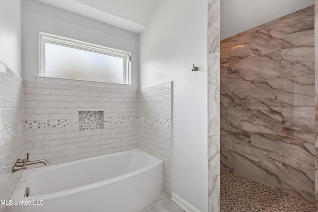 bathroom featuring marble finish floor, tiled shower, and a garden tub