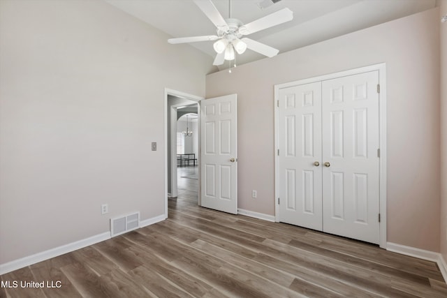unfurnished bedroom with ceiling fan, baseboards, wood finished floors, visible vents, and a closet