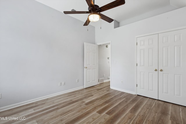 unfurnished bedroom featuring ceiling fan, baseboards, wood finished floors, visible vents, and a closet