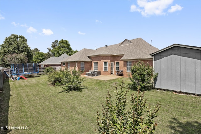 rear view of house featuring roof with shingles, a trampoline, an outbuilding, a patio area, and a shed