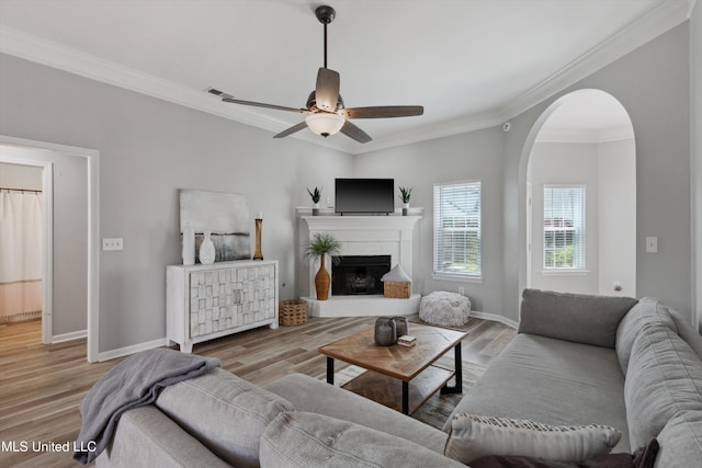 living area with baseboards, ornamental molding, a ceiling fan, and wood finished floors