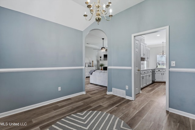 unfurnished dining area with arched walkways, ceiling fan with notable chandelier, baseboards, dark wood-type flooring, and visible vents