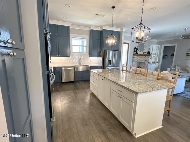 kitchen featuring backsplash, open floor plan, ornamental molding, a kitchen breakfast bar, and stainless steel appliances