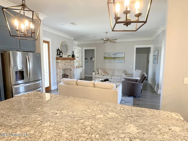 living area featuring a brick fireplace, crown molding, baseboards, a chandelier, and dark wood-style floors