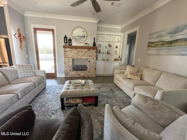 living area with visible vents, a brick fireplace, crown molding, ceiling fan, and dark wood finished floors