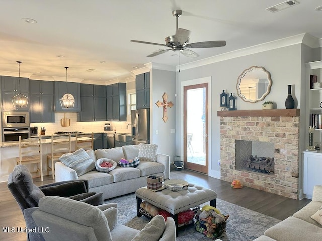 living room featuring visible vents, crown molding, ceiling fan, and wood finished floors