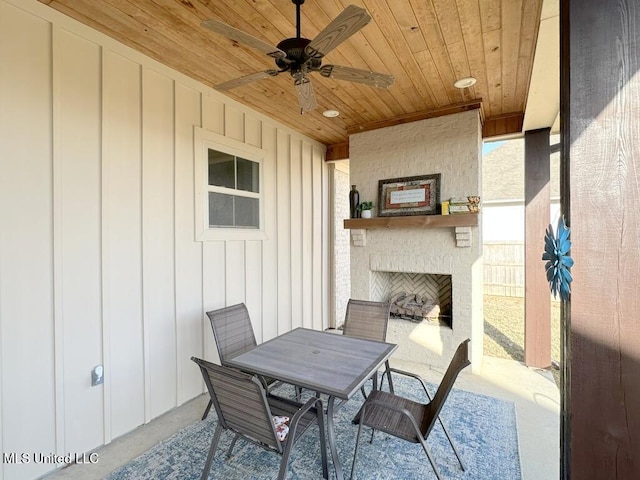 view of patio / terrace featuring outdoor dining area, ceiling fan, and an outdoor brick fireplace