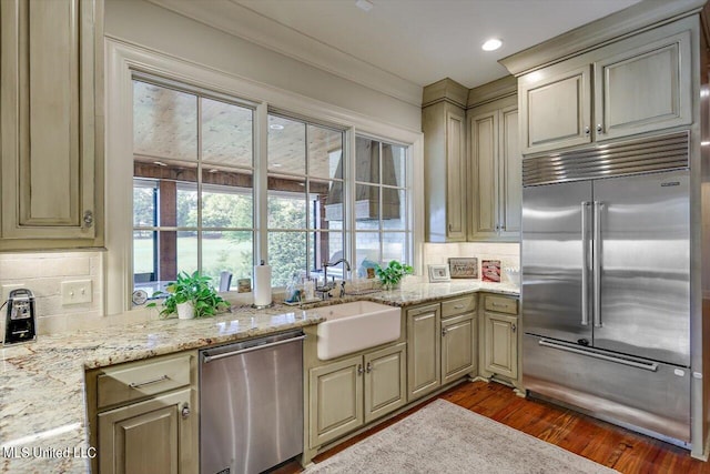 kitchen featuring decorative backsplash, light stone countertops, stainless steel appliances, dark wood-type flooring, and sink