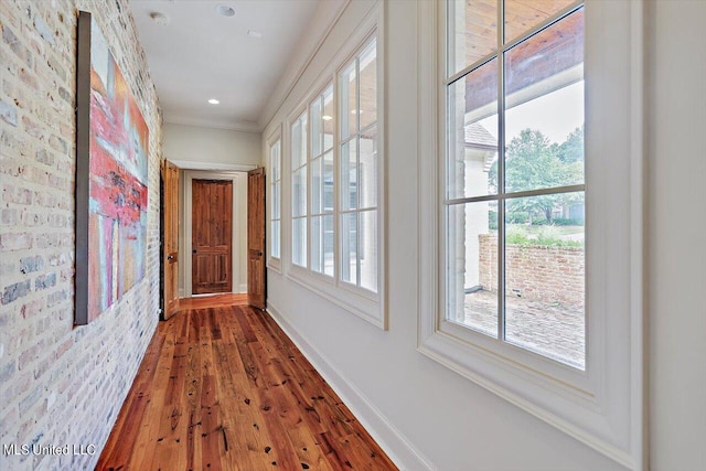 hallway featuring wood-type flooring and brick wall