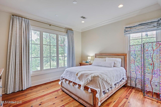 bedroom with multiple windows, ornamental molding, and light wood-type flooring