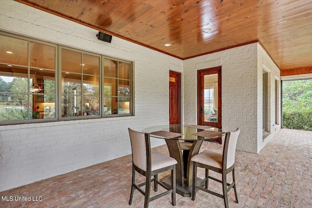 exterior space featuring wood ceiling, brick wall, and ornamental molding