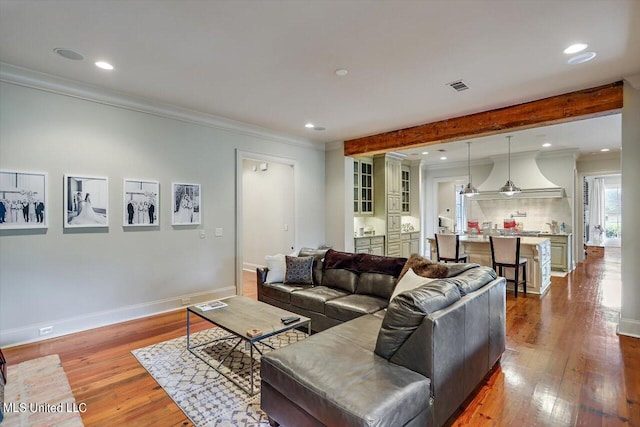 living room featuring beam ceiling, hardwood / wood-style floors, and ornamental molding