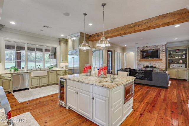 kitchen with built in appliances, decorative light fixtures, a kitchen island, and light hardwood / wood-style flooring