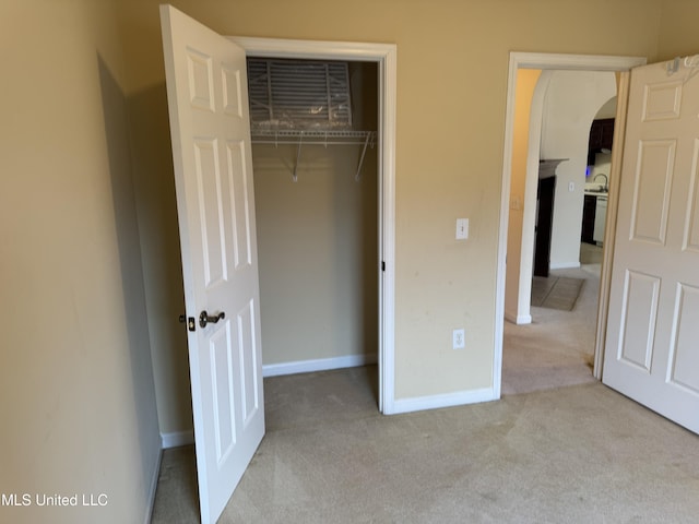 unfurnished bedroom with sink, light carpet, and a closet