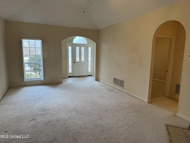 interior space with light carpet, a wealth of natural light, and vaulted ceiling