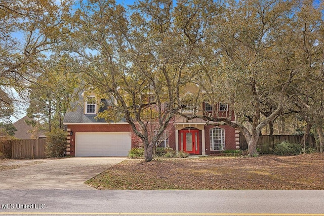 view of front of property featuring brick siding, concrete driveway, and fence